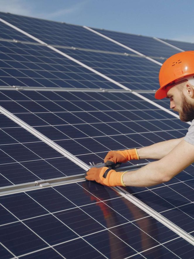 Male worker with solar batteries. Man in a protective helmet. Installing stand-alone solar panel system.