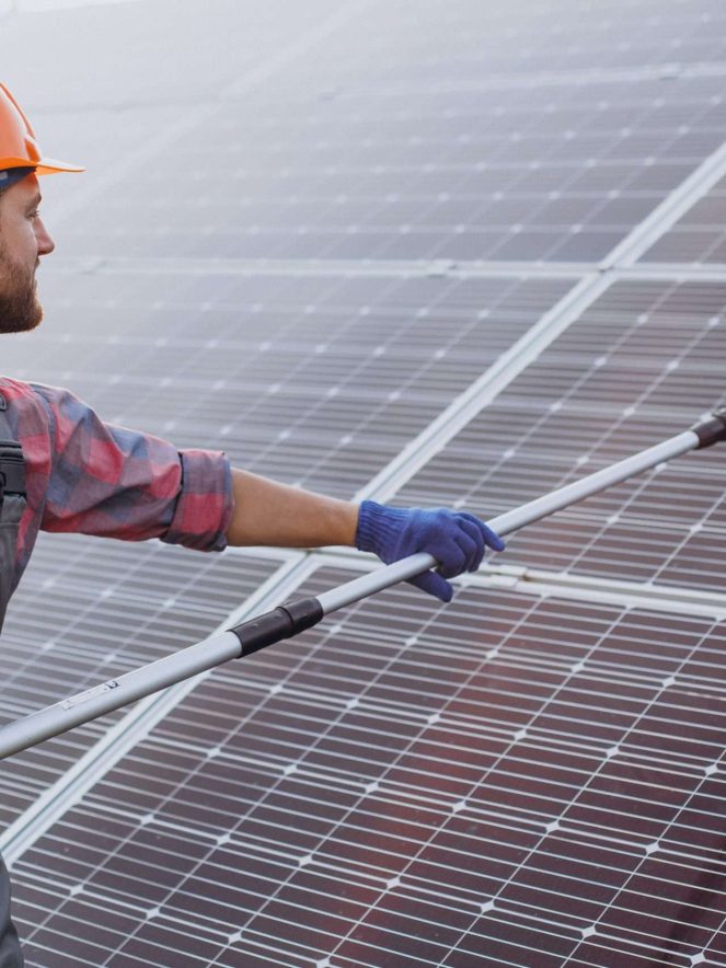 Male worker cleaning solar panels